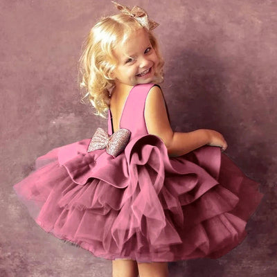 Robe pour fille featuring a cute little girl smiling while wearing a stylish pink dress with layered tulle and a sparkling bow, perfect for special occasions as a dress for lady girls.