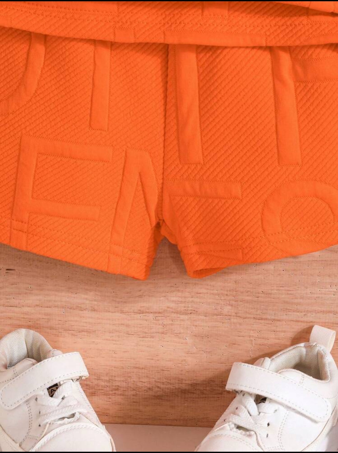 Détail d'un short orange de la marque AURORE LUXURE, mettant en évidence le design texturé pour un ensemble d'été. Idéal pour les jeunes garçons de 4 à 7 ans.