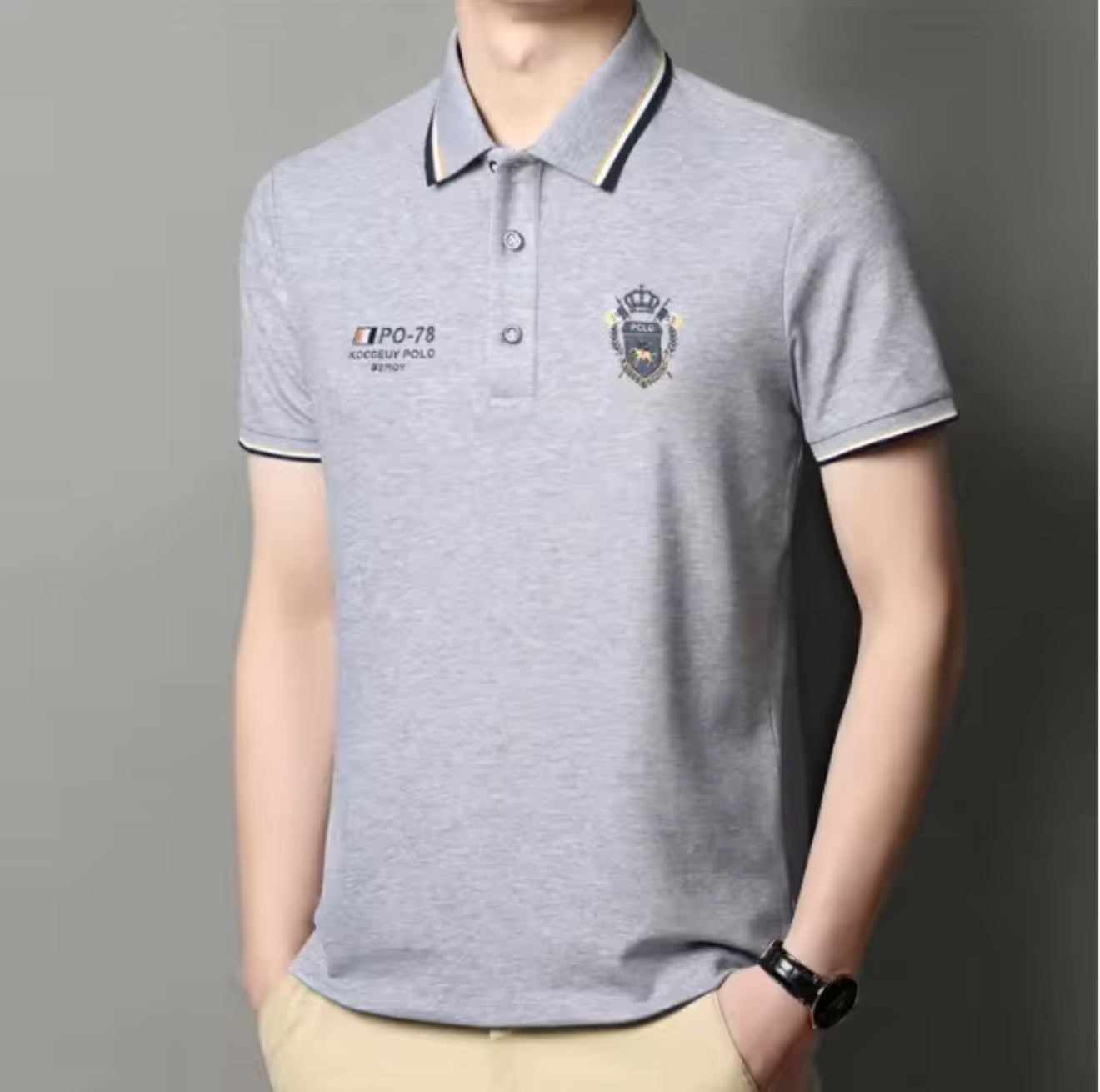 Model wearing gray embroidered short-sleeved polo shirt, breathable, casual and professional style by AURORE LUXURE. Perfect for summer leisure.