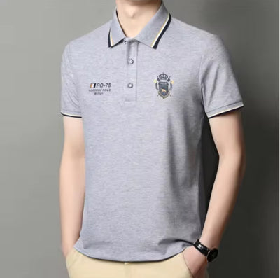 Model wearing gray embroidered short-sleeved polo shirt, breathable, casual and professional style by AURORE LUXURE. Perfect for summer leisure.